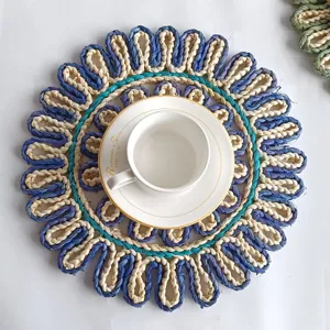 Draufsicht auf ein handgewebtes Platzset aus Maisstroh in Sonnenblumenform mit Tasse.