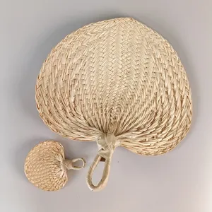 Detailed view of hand-woven palm leaf fans in large and small sizes for summer cooling