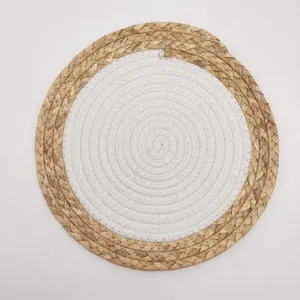 Top view detail of a round two-tone placemat woven from cotton rope and natural straw