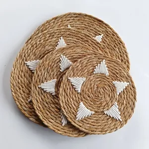 Detail view of circular woven straw placemats featuring white embroidered triangle patterns
