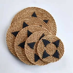 Close-up detail of various sized round woven grass placemats with black embroidery