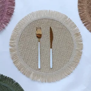 Detailed view of round braided placemat with fringe, elegant table decoration for kitchen.