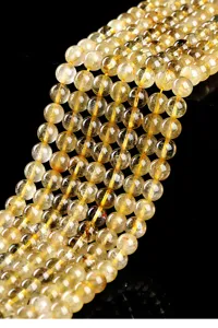 Macro detail of natural golden rutilated quartz round loose beads for DIY jewelry