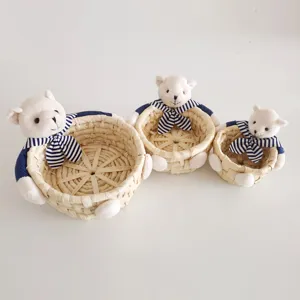 Straw woven storage baskets set of three with cute plush bear and striped bow decor.