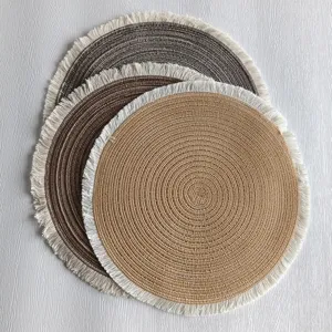 Close-up detail of stylish round braided cotton placemat featuring decorative white fringe.
