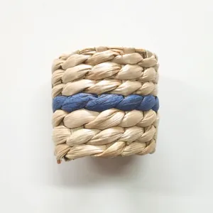 Portatovaglioli in paglia intrecciata a mano con dettaglio blu per tavola elegante.