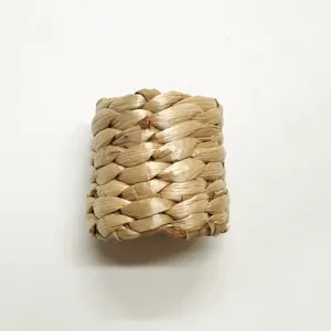 Dettaglio anello per tovagliolo in paglia naturale, trama rustica intrecciata per tavola.