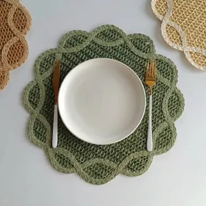 Close-up of a flower-shaped green woven paper placemat with a white plate.
