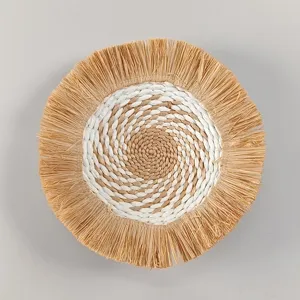 Bohemian round straw woven wall hanging with natural raffia fringe detail for home decor.