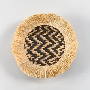 Bohemian round straw woven wall hanging with fringed edge and chic black tan pattern decor.