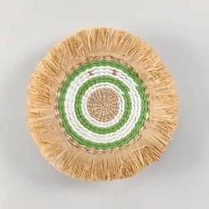 Detailed view of the bohemian woven wall hanging with natural raffia fringe and green white rings.