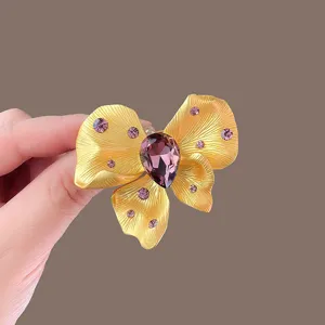 Close-up detail of luxury gold butterfly brooch with stunning purple rhinestone crystals.