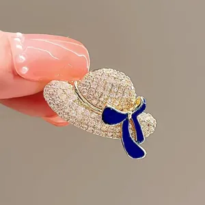 Detail view of a sparkling crystal hat-shaped brooch with an elegant blue bow decoration