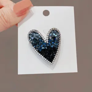 Detailed macro view of an asymmetric blue and black heart brooch with crystal border