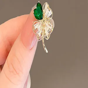 Macro detail of high-end four-leaf clover brooch with green heart-shaped crystal and clear stones