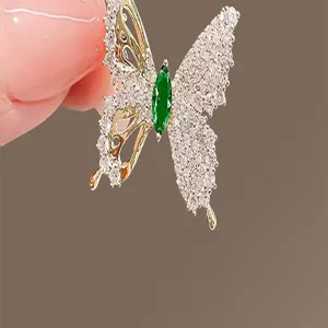 Close-up of elegant butterfly brooch with green gemstone and micro-pave stones