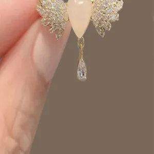 Macro detail of heart-shaped winged brooch with dangling crystal and sparkling rhinestones