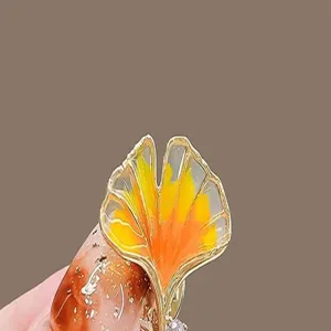 Detailed close-up of a yellow ginkgo leaf brooch featuring an elegant gold-toned metal frame