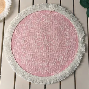 Close-up detail of a pink Bohemian round cotton placemat with white fringe and mandala print.