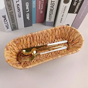 Hand-woven natural straw oval basket for bread and fruit storage with gold cutlery