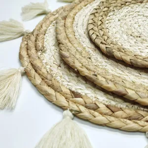 Detailed shot of round woven straw placemat with tassel edge, natural texture design.