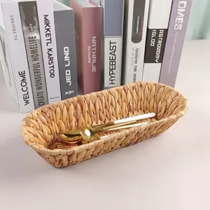 Detailed view of hand-woven oval grass basket holding a golden cutlery set