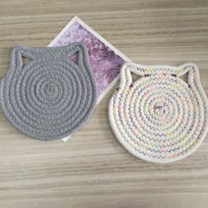 Detailed view of handmade cat-ear shaped cotton rope coasters on wooden background
