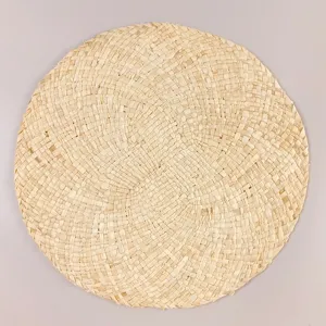 Dettaglio in primo piano della tovaglietta rotonda in mais intrecciato a mano, trama rustica.
