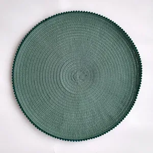 Round woven placemat texture detail view with cute pom-pom edge for dining table decor.