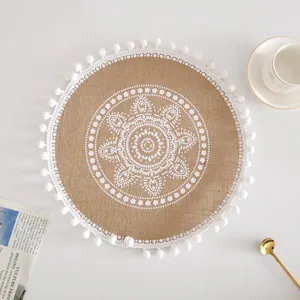 Rundes gewebtes Tischset aus Jute mit weißem Mandala-Muster und dekorativer Bommel-Borte.
