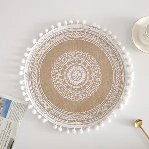 Draufsicht auf ein rundes Jute-Tischset mit weißem Mandala-Muster und Pompon-Verzierung.