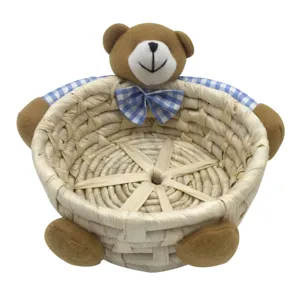 Cute corn husk woven storage basket with adorable plush bear decoration for desktop organizing.