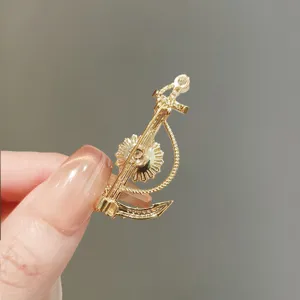 Detalle de broche de ancla dorada, elegante pin náutico para accesorio de traje de mujer.