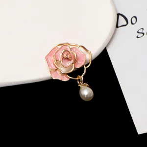 Close-up of elegant pink enamel camellia flower brooch with pearl pendant for suit coat pin.