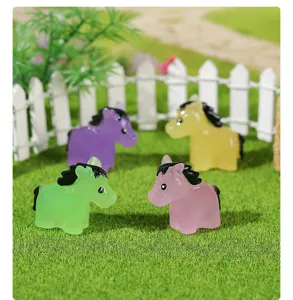 Detailed view of four colorful luminous mini horse figurines on artificial grass