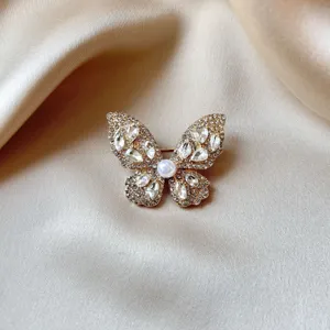 Close-up detail of the elegant butterfly brooch, shimmering rhinestones with central pearl.