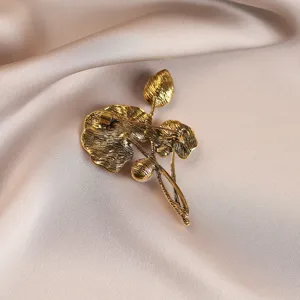 Macro view showing the back pin mechanism of a vintage gold-finish lotus leaf brooch.
