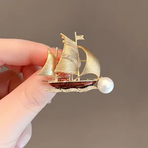 Exquisite sailboat brooch detail, elegant metal design with sparkling rhinestones and pearl accent.