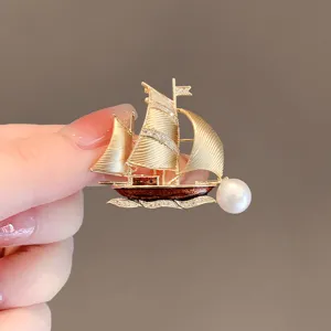 Exquisite sailboat brooch with pearl accent, elegant gold metal pin for suit and clothing.