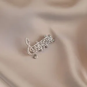 Close-up of elegant silver musical staff brooch with sparkling crystals on silk background