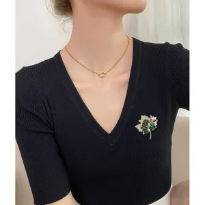 Exquisite maple leaf brooch and gold necklace shown on a model's black V-neck top
