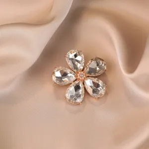Crystal flower brooch detail shot showcasing the sparkling pear-shaped rhinestones and golden metallic setting.
