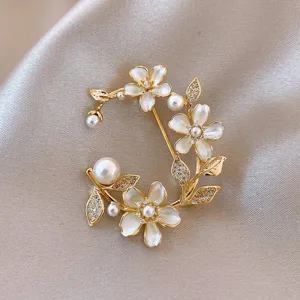 Detail van de bloemenbroche met delicate witte bloblaadjes, parels en sprankelende kristallen.