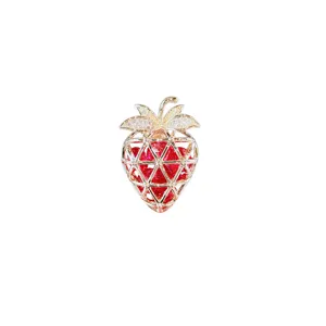 Close-up detail of the elegant strawberry brooch featuring gold mesh and red crystals.