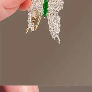 Exquisite butterfly brooch detail with sparkling crystals and a vibrant green center stone.