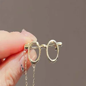 Gold glasses shape brooch detail close up view, elegant metallic accessory pin for suit.