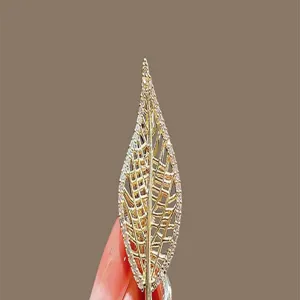 Detailed closeup of a gold leaf brooch, shimmering crystal stones, exquisite accessory detail.