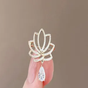 Macro view of an elegant lotus flower brooch featuring sparkling crystals and a teardrop charm