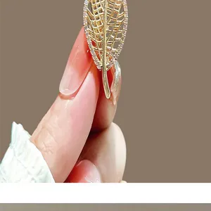 Close-up detail of an elegant gold leaf brooch with sparkling rhinestone accents.