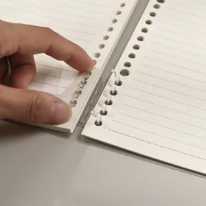 Close-up of a loose-leaf spiral notebook with transparent rings and horizontal lined paper